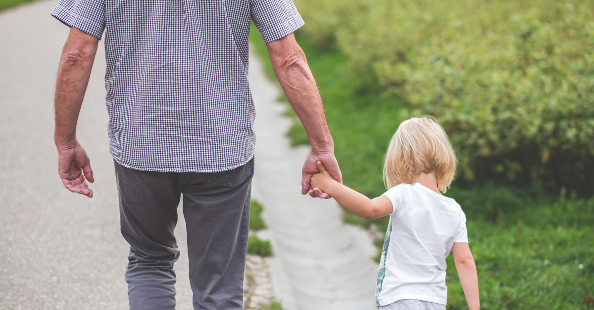 Child holding her grandfather's hand on a walk