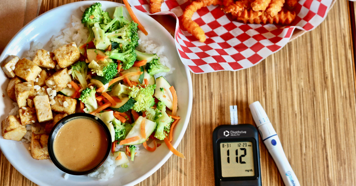 Tofu rice bowl and sweet potato fries on a table with a Diathrive glucometer