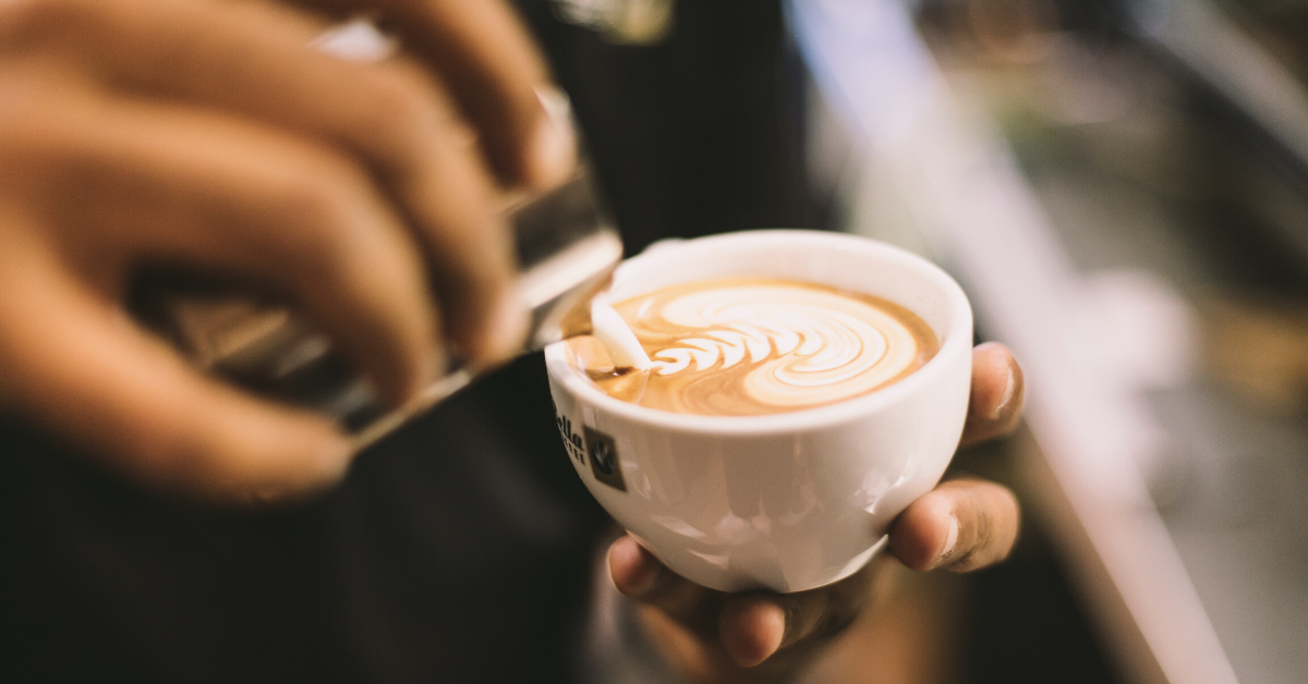 Barista pouring a fancy cafe latte.