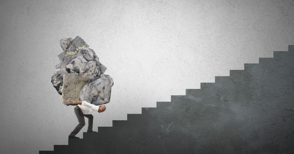 Man carrying several boulders up a long flight of stairs