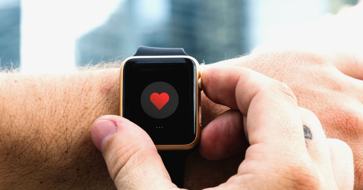 A man wearing an Apple Watch with a heart icon showing on the screen