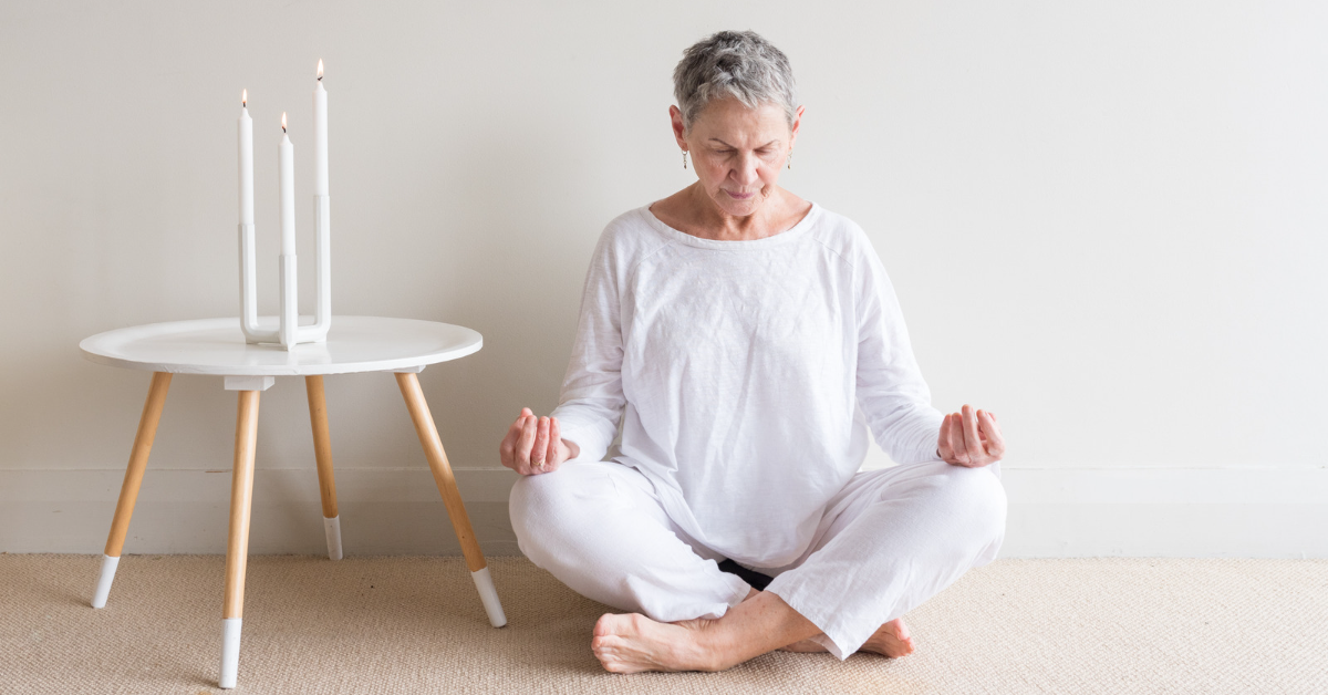 Woman meditating near candles on an end table