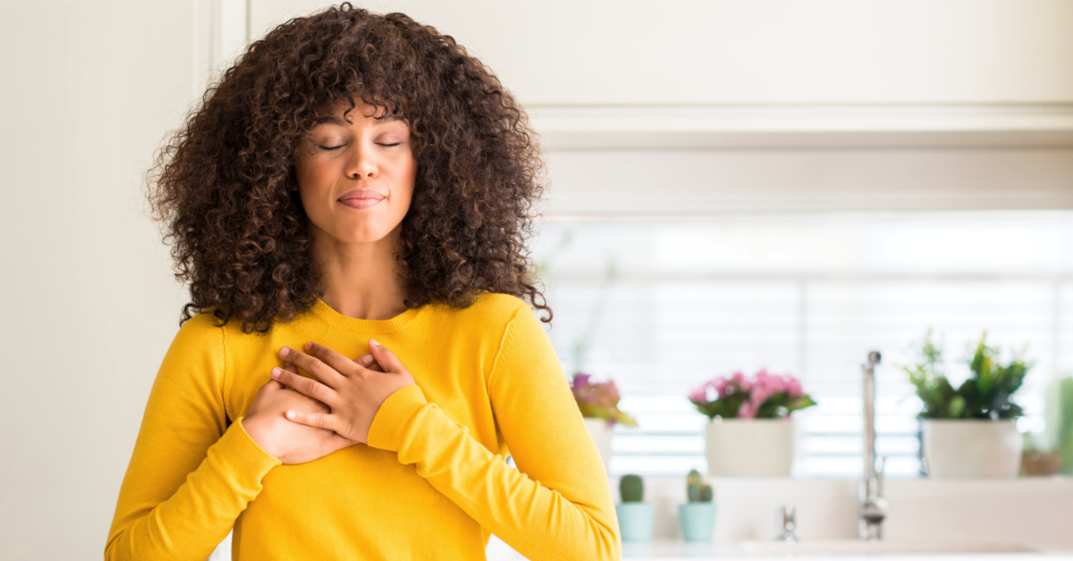 Woman smiling with eyes closed and hands over heart