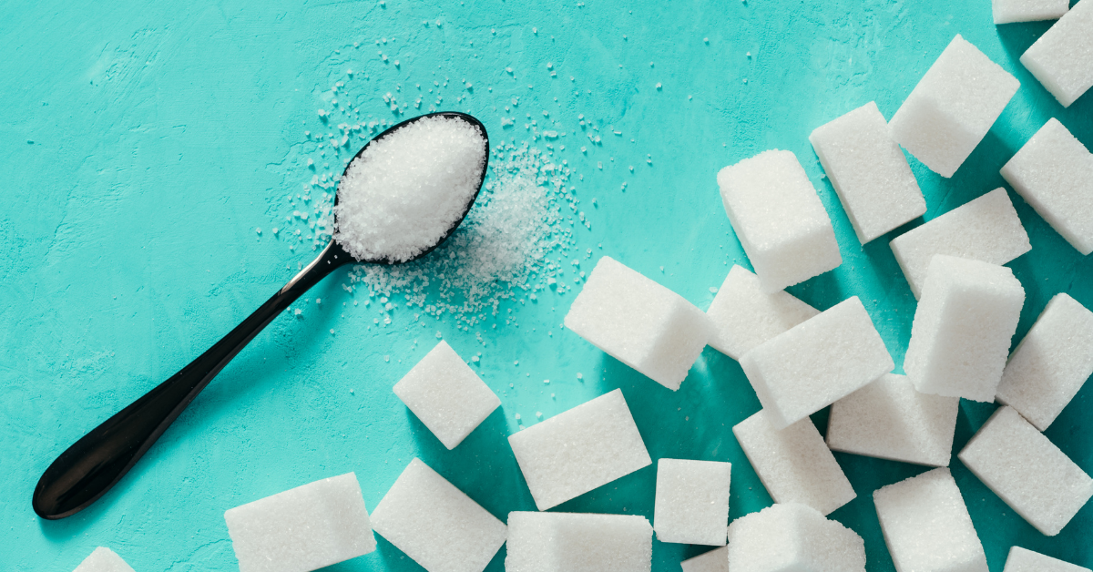 A spoon full of sugar next to several sugar cubes