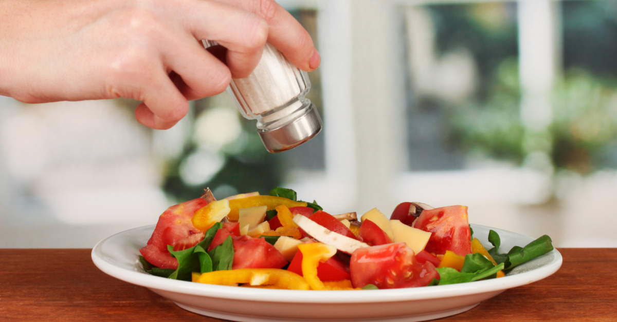 Sprinkling salt onto salad with a salt shaker